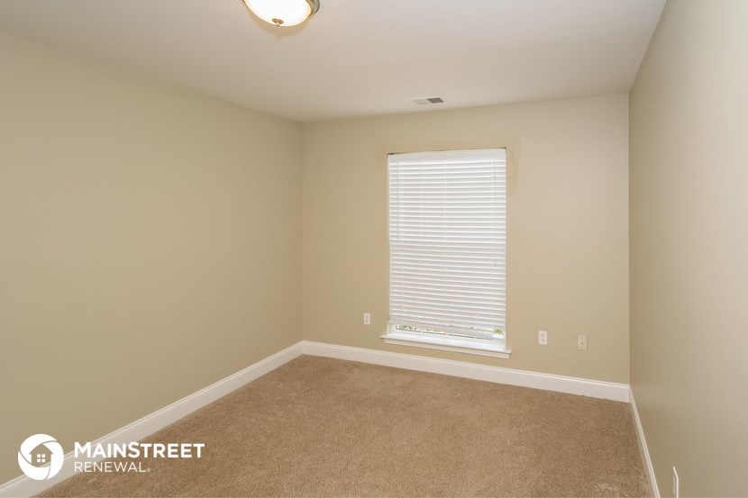 the upstairs bedroom has a large window and carpeted flooring