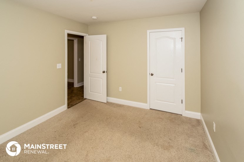 a carpeted room with two doors and a door to a closet