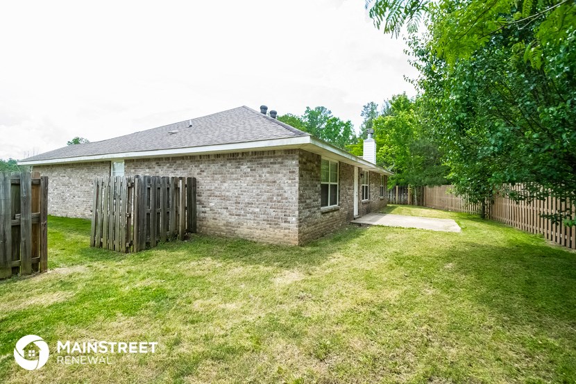 the backyard of a brick house with a wooden fence and grass