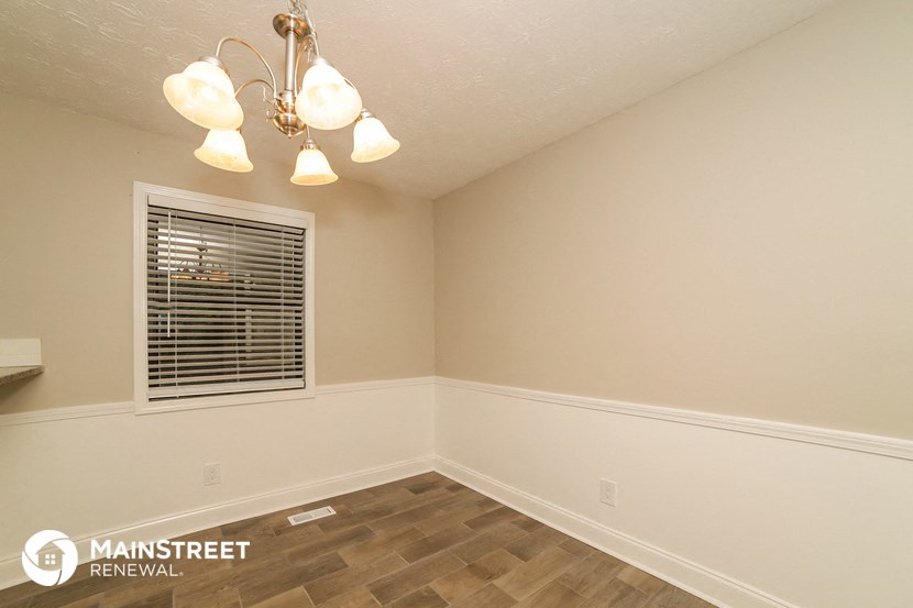 the living room of a house with a window and wood flooring