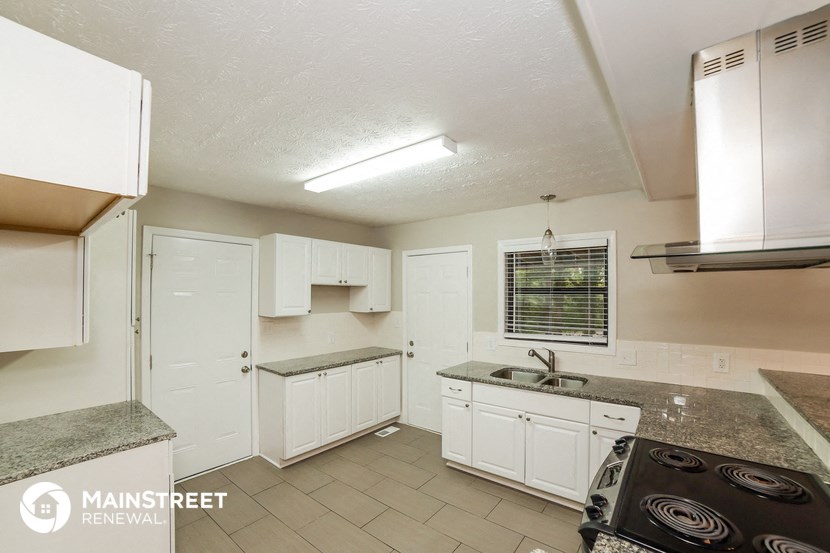 a kitchen with white cabinets and a stove and a sink