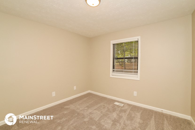 the upstairs bedroom with carpet and a window