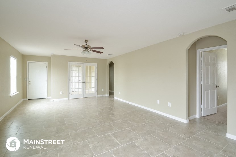 an empty living room with a ceiling fan