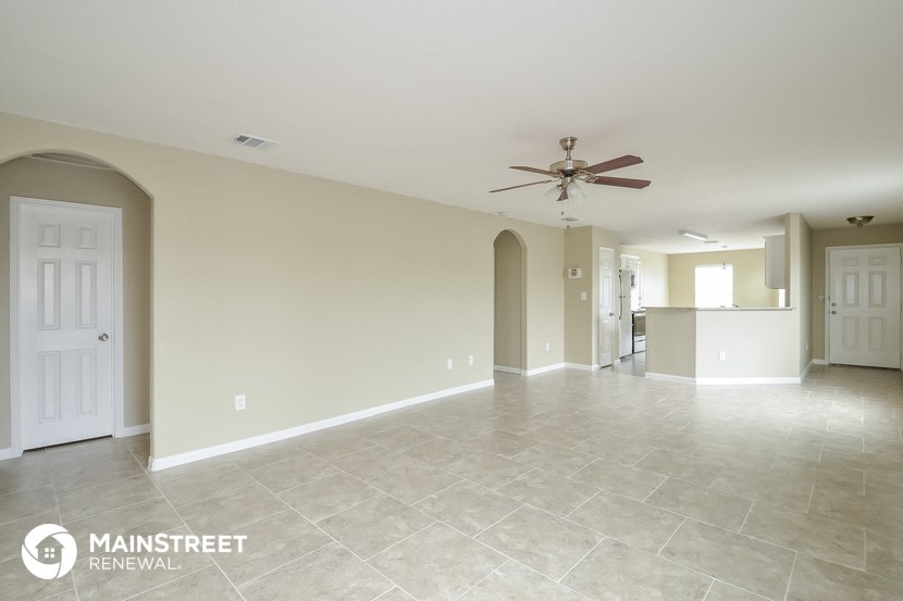 an empty living room with tile flooring and a ceiling fan