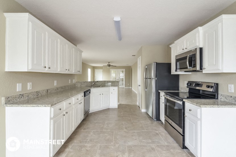 a large kitchen with white cabinets and stainless steel appliances