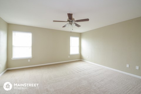 a living room with a ceiling fan and a white carpet