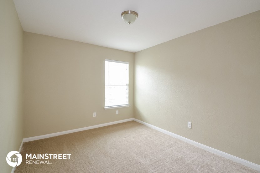 the upstairs bedroom with carpeting and a window