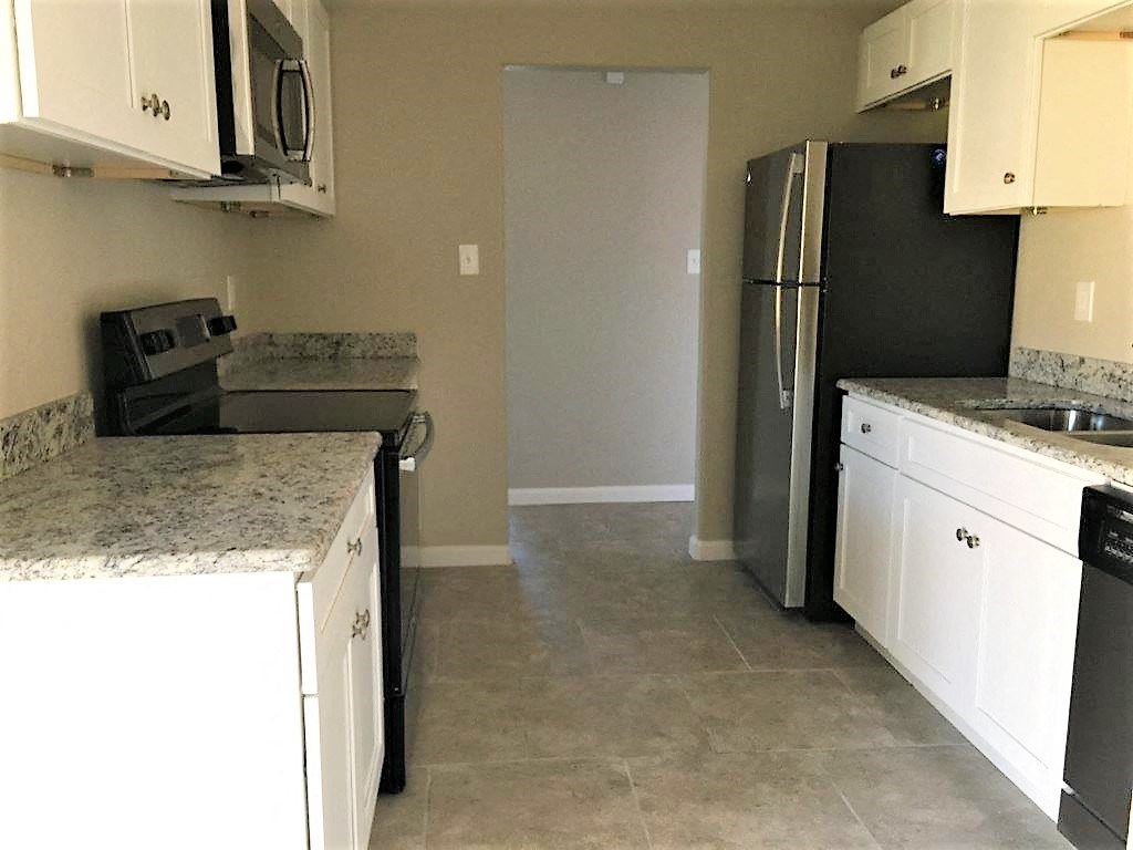 a kitchen with white cabinets and a black refrigerator