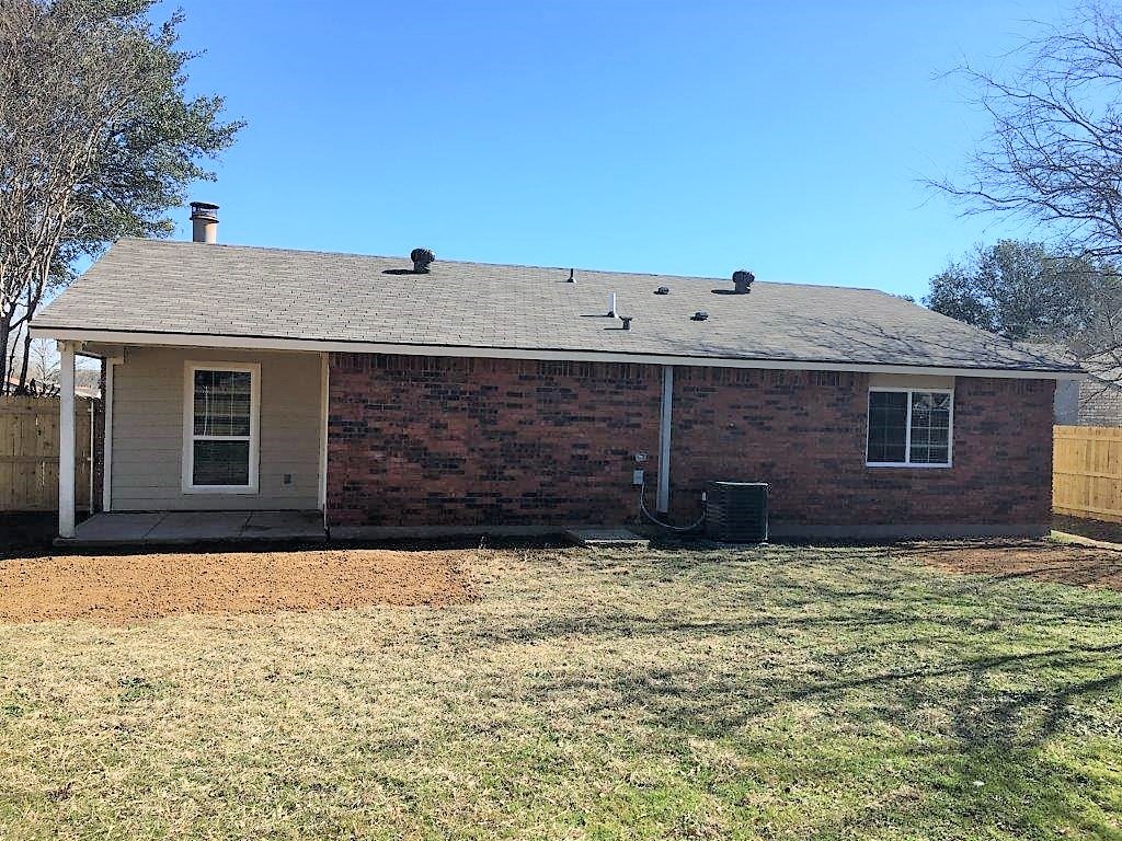 a small brick house with a yard and a fence