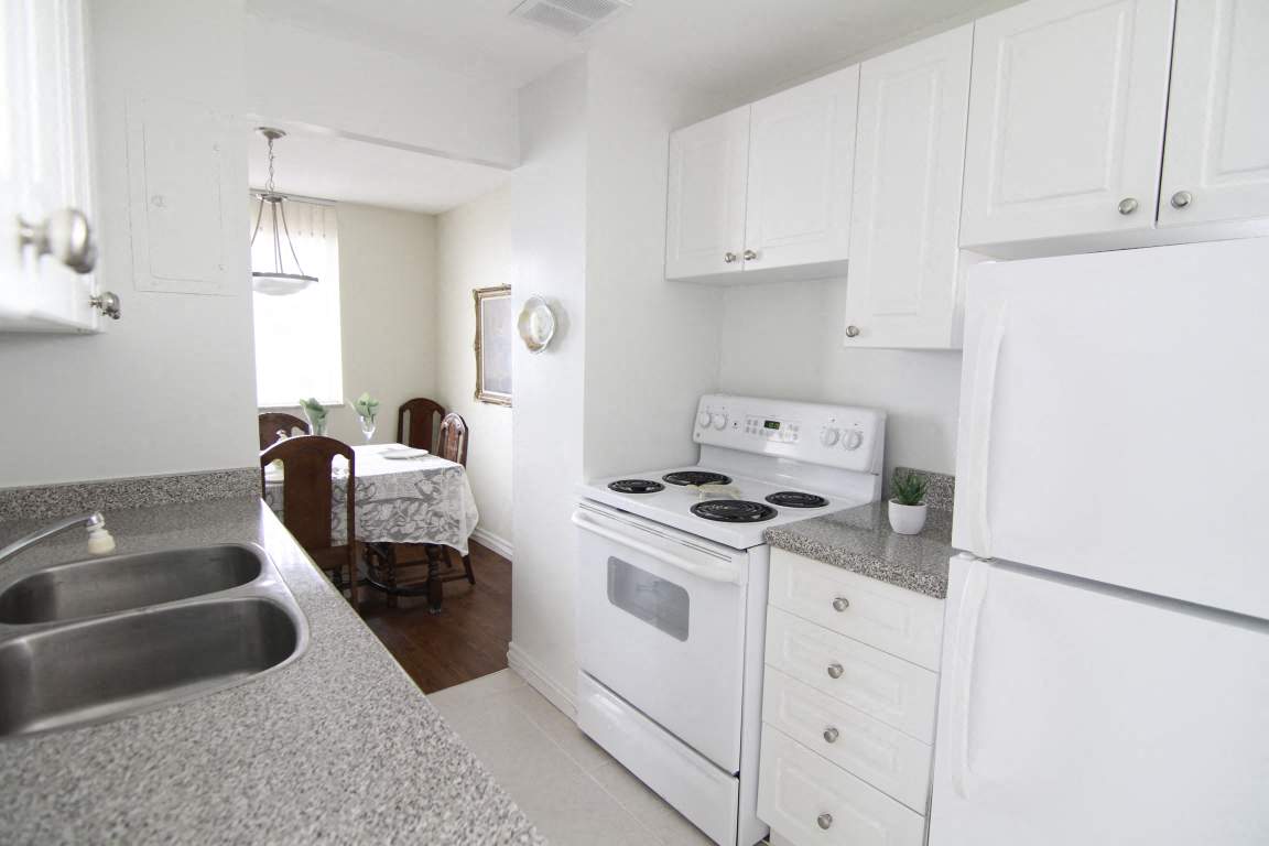 A kitchen with white appliances and cabinets.