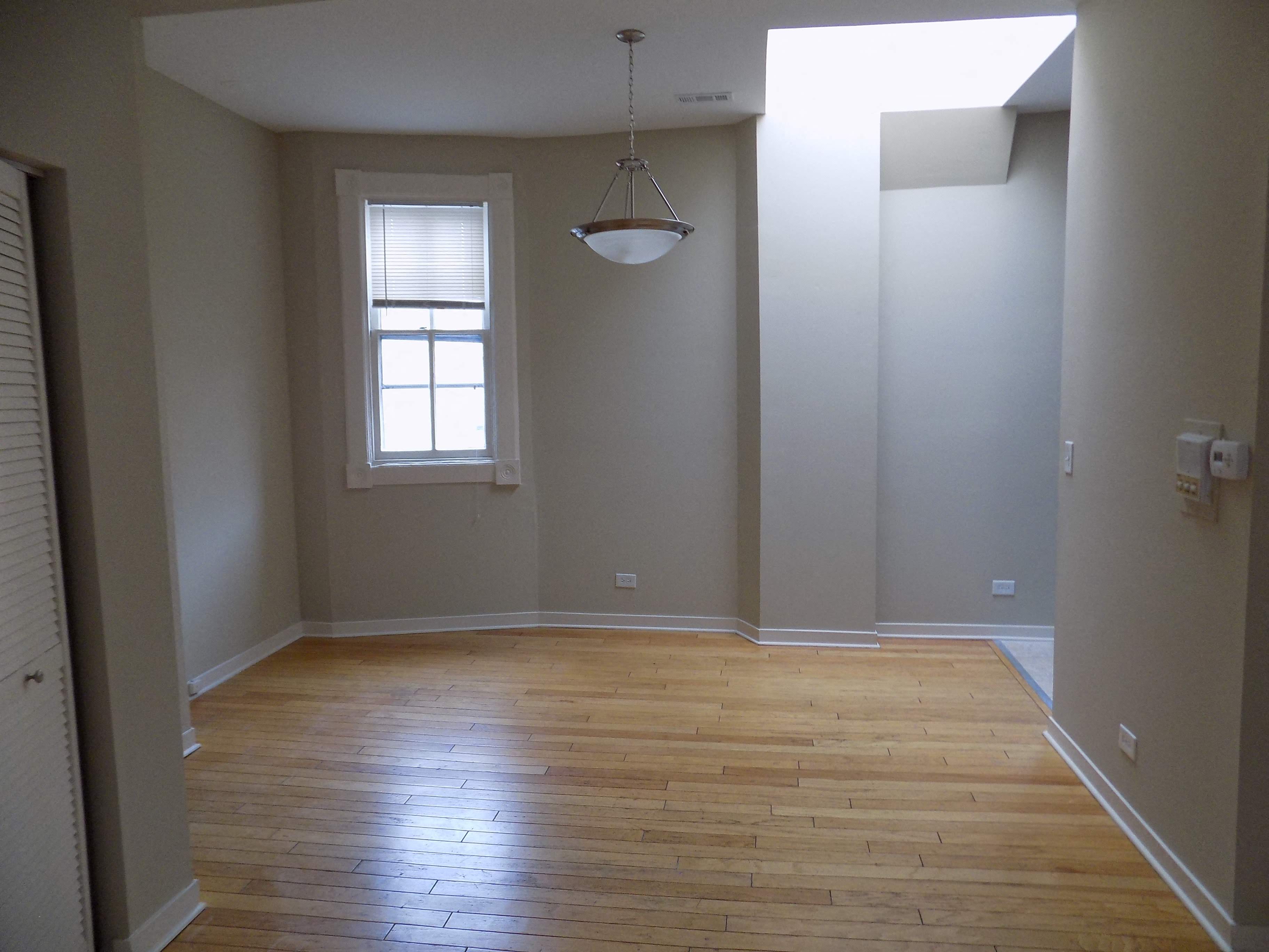 an empty living room with wood floors and a window