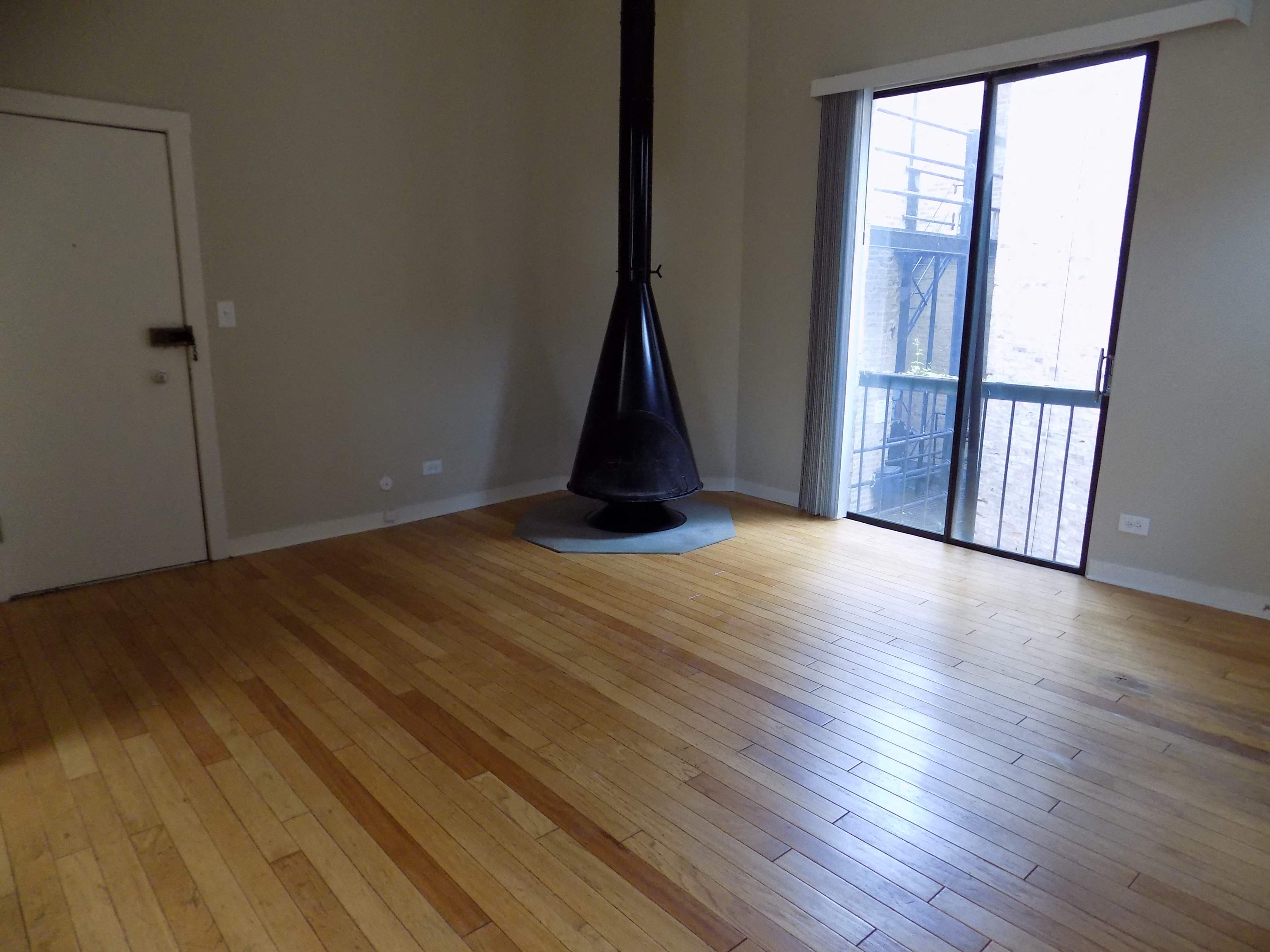a living room with a hardwood floor and a door to a balcony