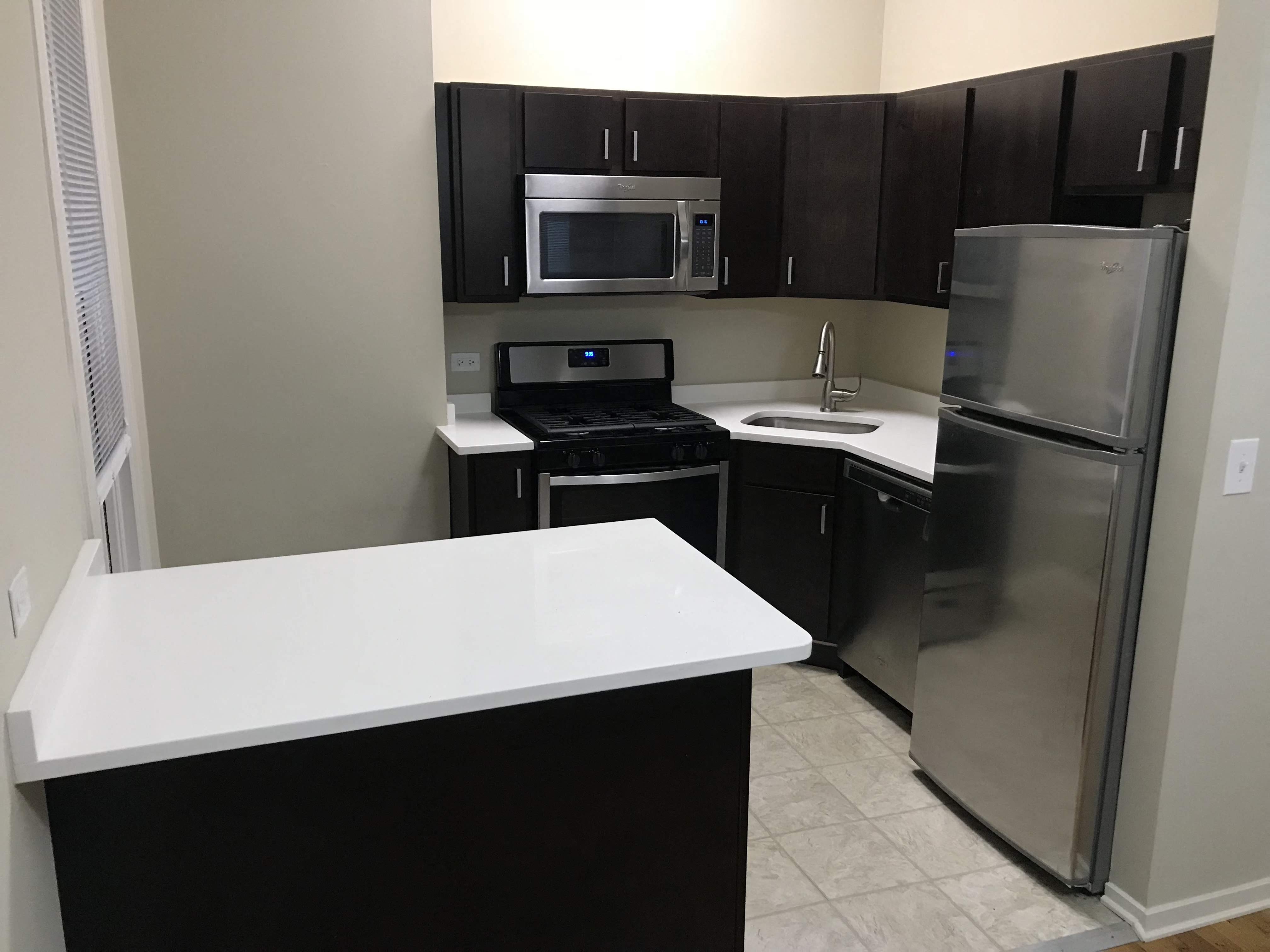 a kitchen with a white counter top and a stainless steel refrigerator