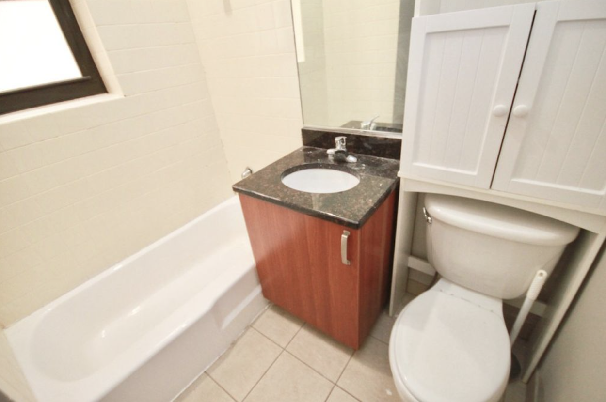 Bathroom with full tub and extra storage above the toilet