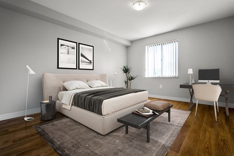 A bedroom with a large bed, a desk with a chair, and a rug on the floor.