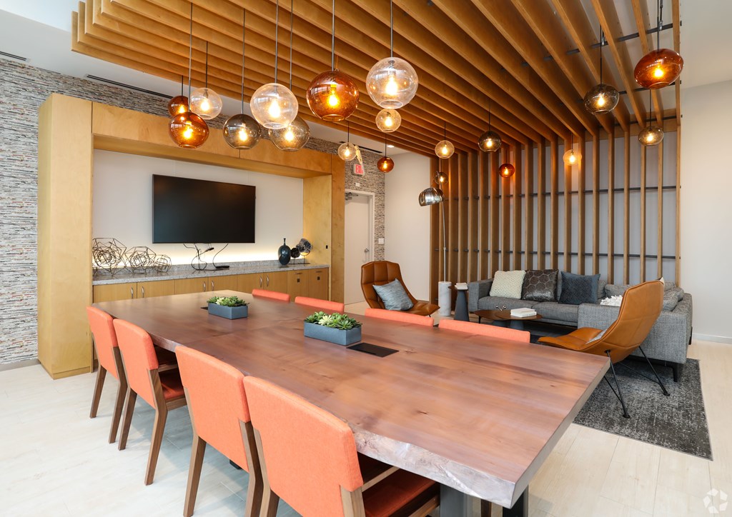 A modern dining room with a long wooden table and orange chairs.