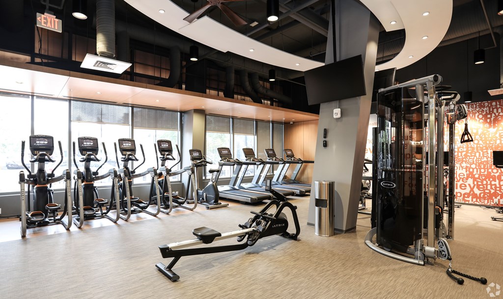 A gym with a variety of equipment including treadmills, weights, and exercise machines.