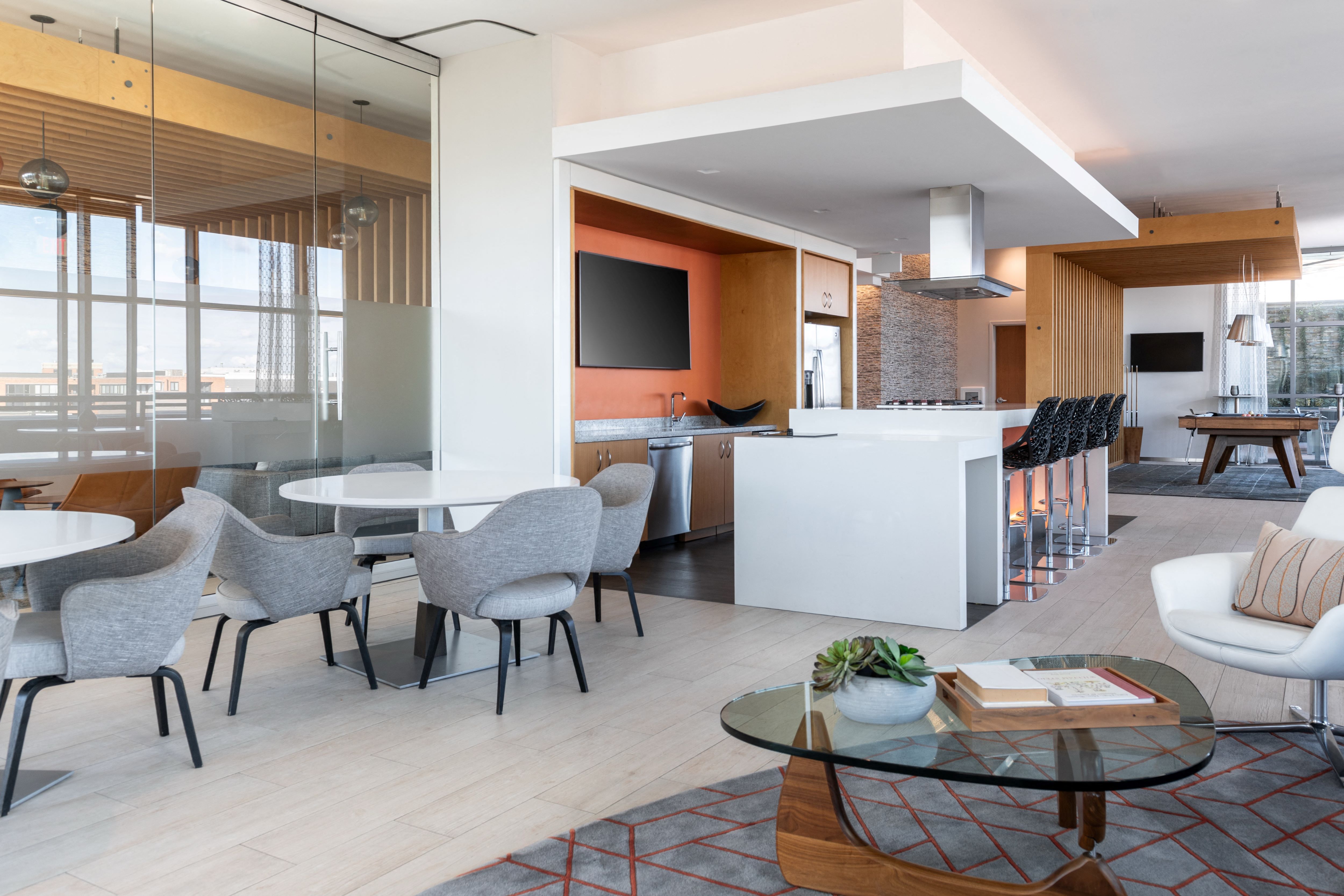 A modern living room with a glass table and grey chairs.