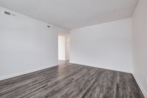 an empty living room with white walls and wood flooring