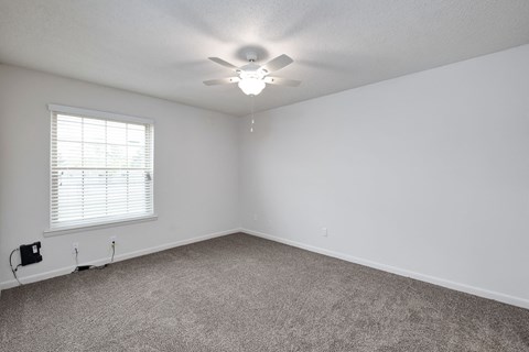 an empty bedroom with a ceiling fan and a window