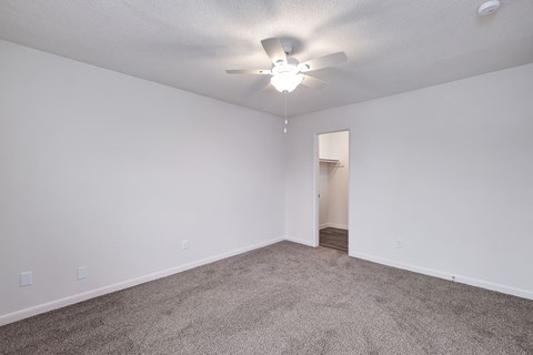 an empty living room with white walls and a ceiling fan