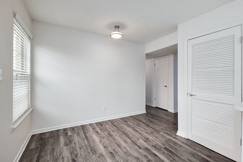 the spacious living room with white walls and wood flooring