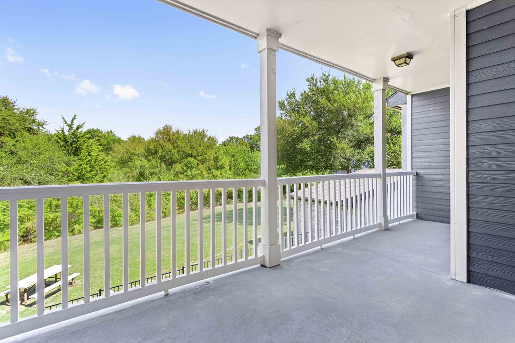 A white porch with a white railing and a white pillar.