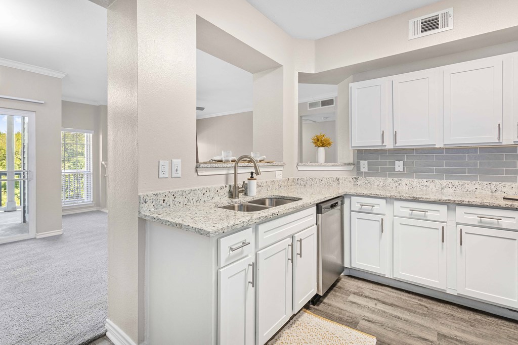 A kitchen with white cabinets and a granite countertop.