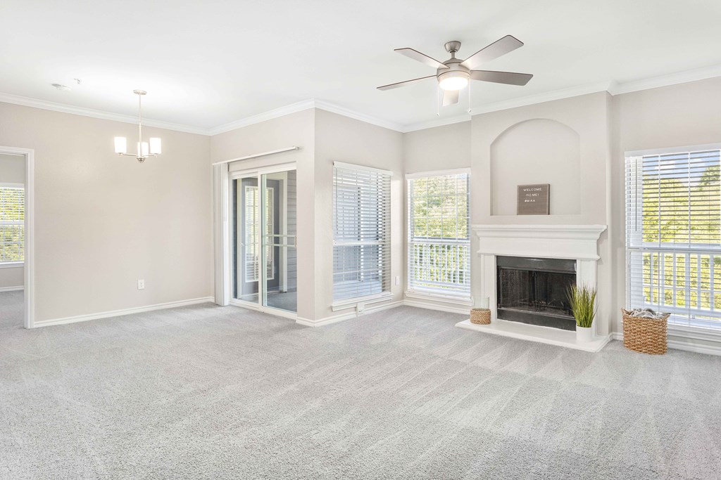A spacious living room with a fireplace and a ceiling fan.