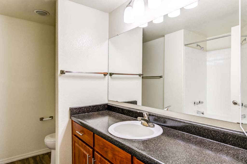 The Palms Apartments Bathroom with brown cabinets and dark counter tops