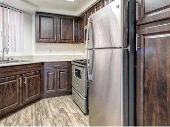 Ingleside Apartments kitchen with light brown floors, dark brown cabinets and stainless steel appliances - Photo Gallery 13