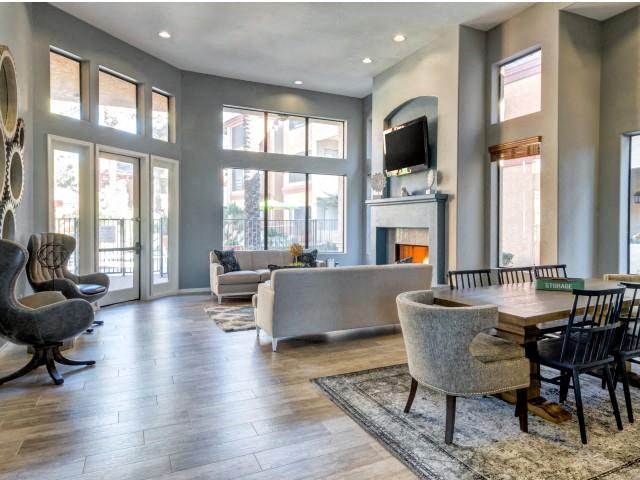 Ingleside Apartments Clubhouse with two couches, a dining table, and brown side chairs. Large windows look out to the pool