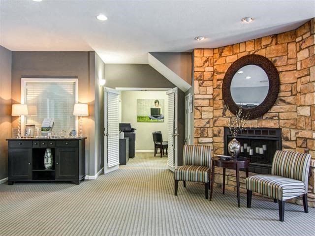 a living room with chairs and a stone fireplace
