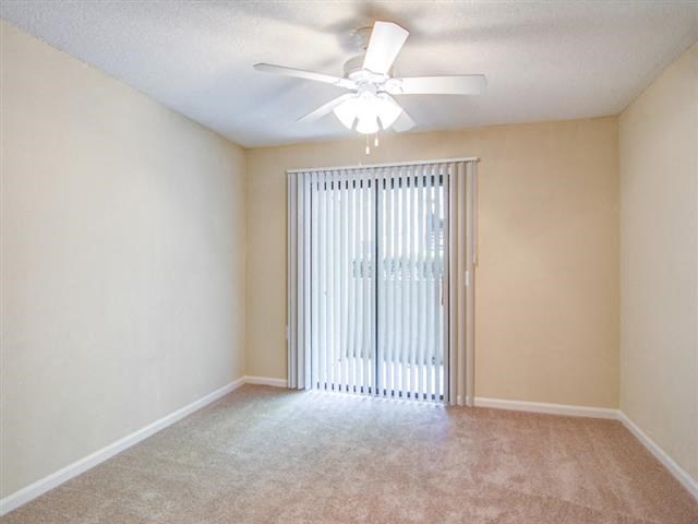 an empty living room with a ceiling fan and a window