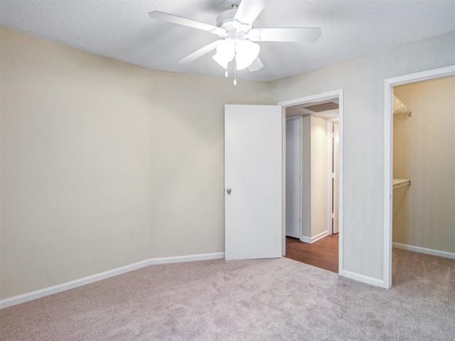 an empty living room with a ceiling fan and a closet