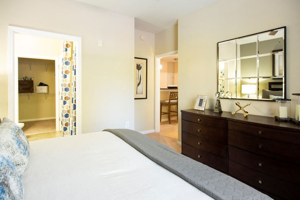 a bedroom with a bed and a dresser and a mirror