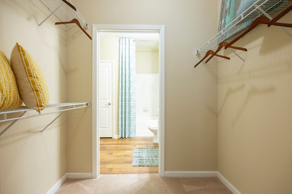 a walk in closet with a door open to a bathroom
