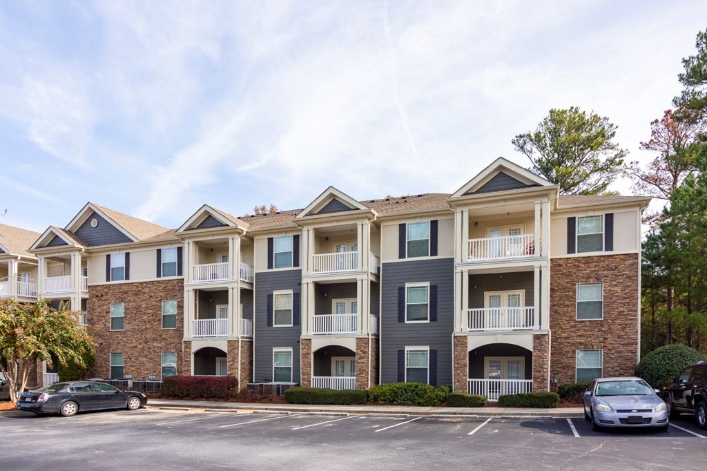 an apartment building with cars parked in a parking lot