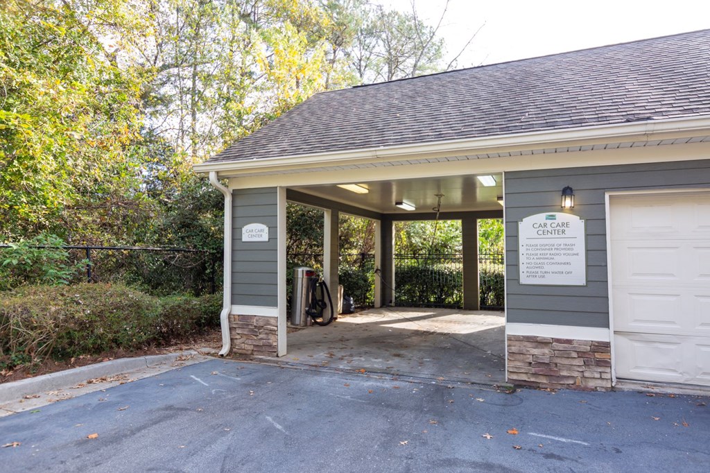 the entrance to a parking lot with a gray building with a sign on the door