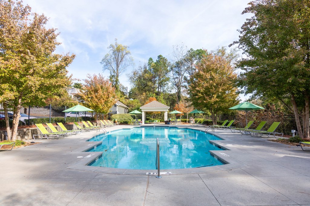 a swimming pool with chairs and trees around it