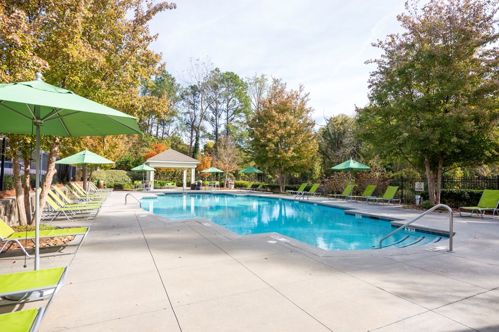 a swimming pool with chairs and umbrellas and trees around it