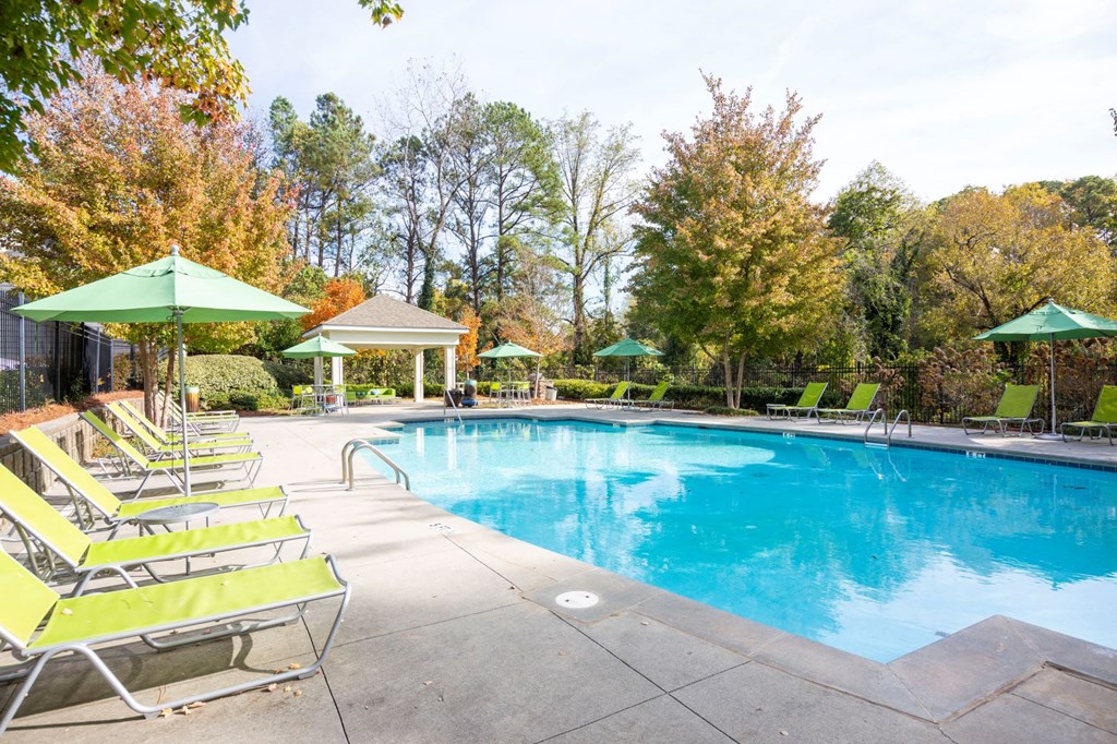 a swimming pool with chairs and umbrellas next to a resort style pool