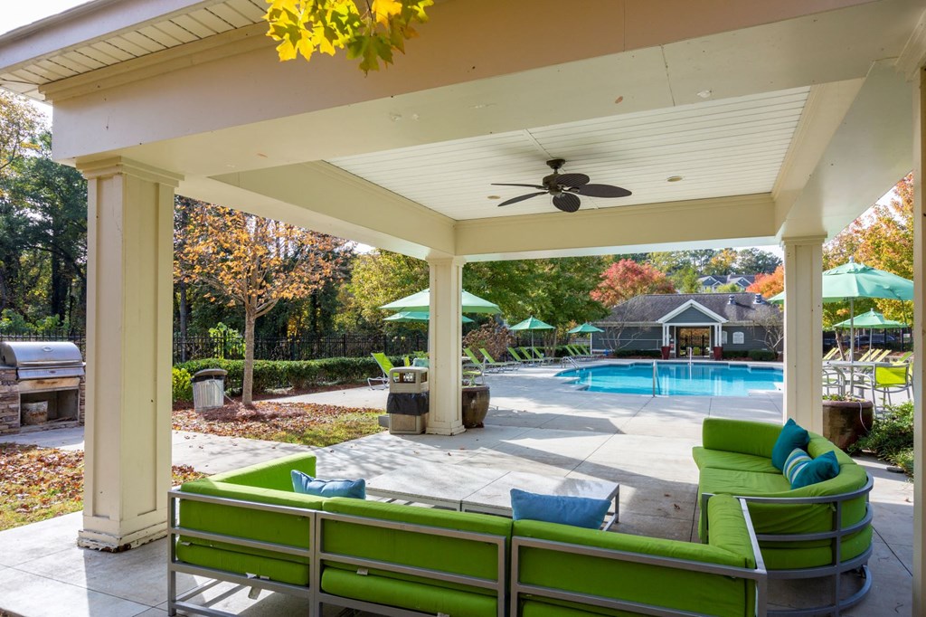 a covered patio with a pool in the background