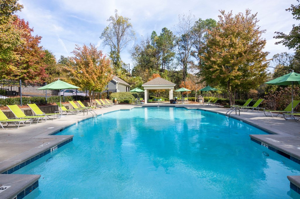 a swimming pool with chairs and umbrellas next to a resort style pool
