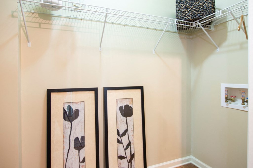 a closet with two pictures and a clothes rack on the wall