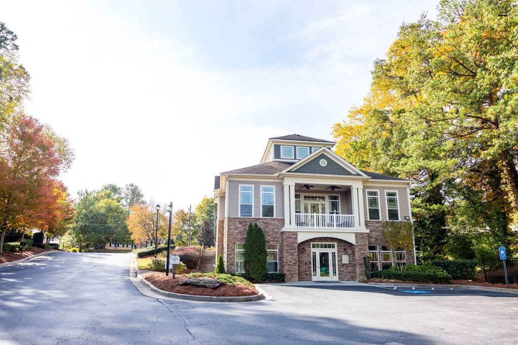 the front of a brick house with a driveway and trees