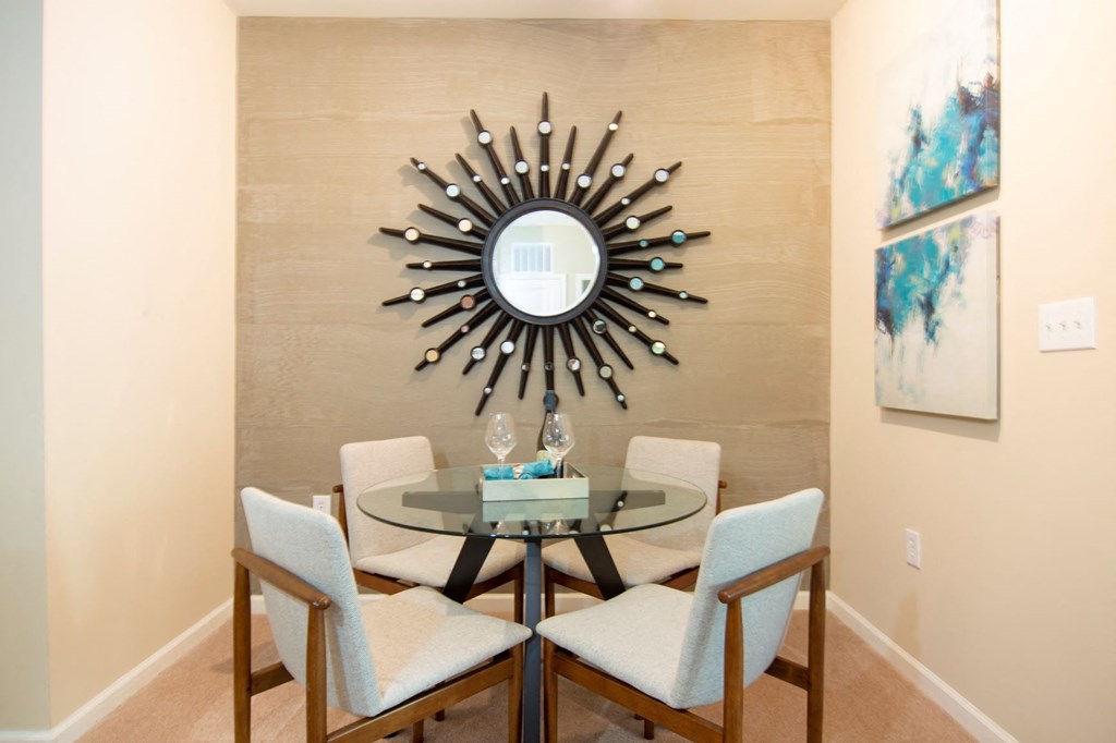 a dining room with a table and a sunburst mirror
