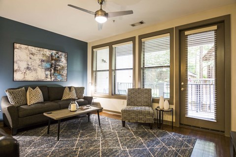 a living room with a couch and a chair and a ceiling fan