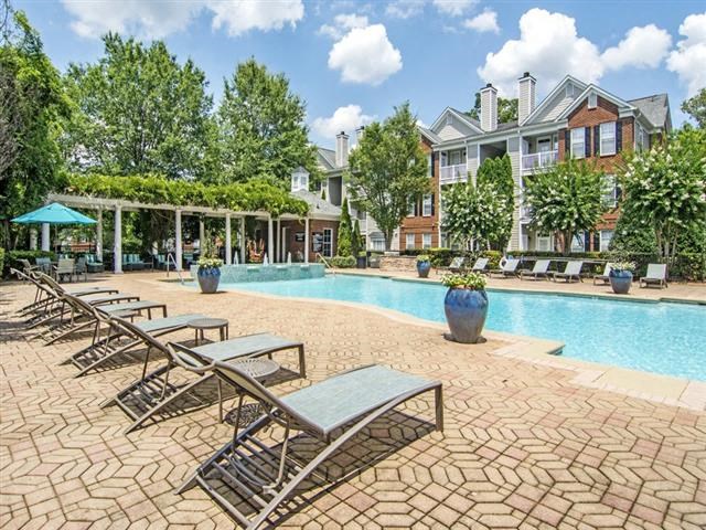 a swimming pool with chairs and a building in the background