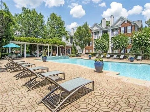 a swimming pool with chairs and a building in the background